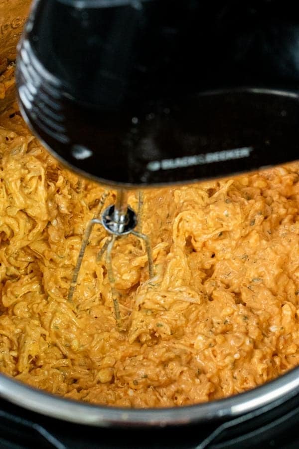 mixing the buffalo chicken dip in the Instant Pot with a hand mixer