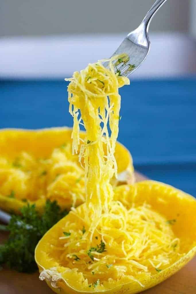 Spaghetti Squash on a fork with parsley and pepper cooked in the instant pot pressure cooker. a strand of spaghetti squash