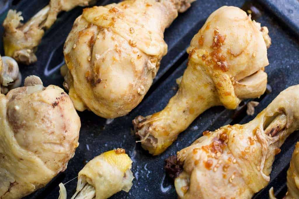 Pressure cooked chicken leg drumsticks with a coating of teriyaki sauce on a broiler pan