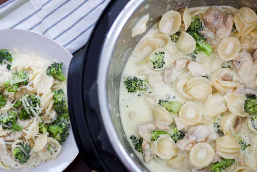 a bowl of chicken con broccoli on a dark background with orecchiette noodles next to the instant pot
