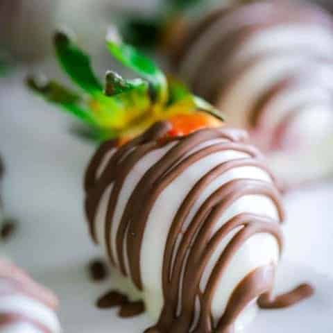 close up of one strawberry covered in white chocolate drizzled with milk chocolate