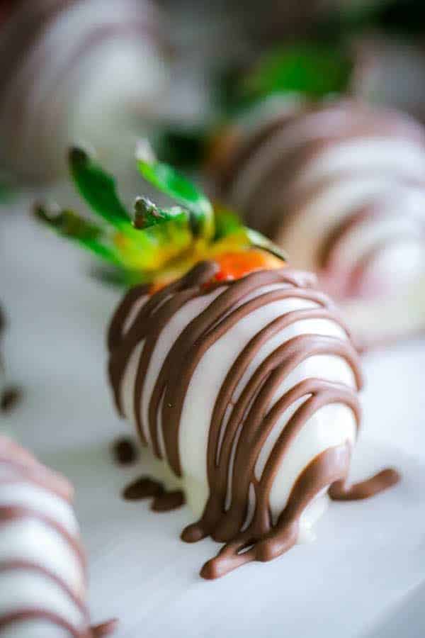 close up of one strawberry covered in white chocolate drizzled with milk chocolate