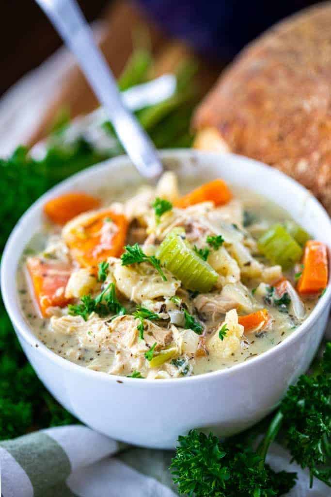 Chicken noodle soup with bread in a white bowl