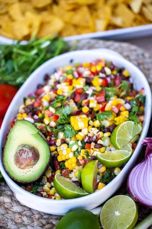 bowl of salsa with an avocado and lime