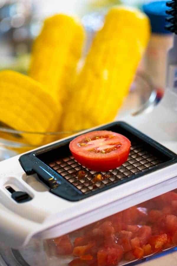 veggie chopper with tomato with corn in the background