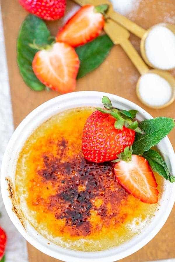 creme brulee with mint and strawberries on a wooden board