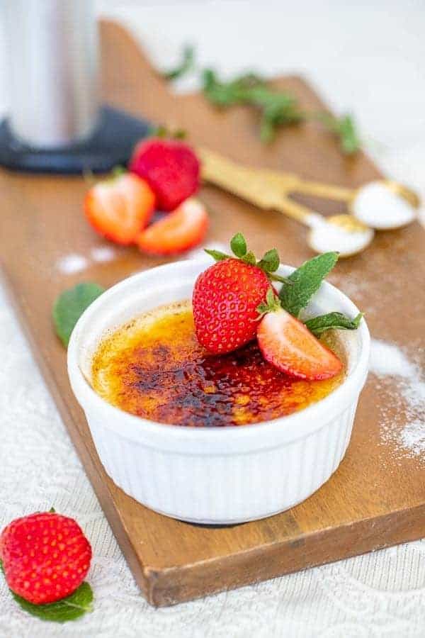 creme brulee with strawberries, mint, and sugar on a board