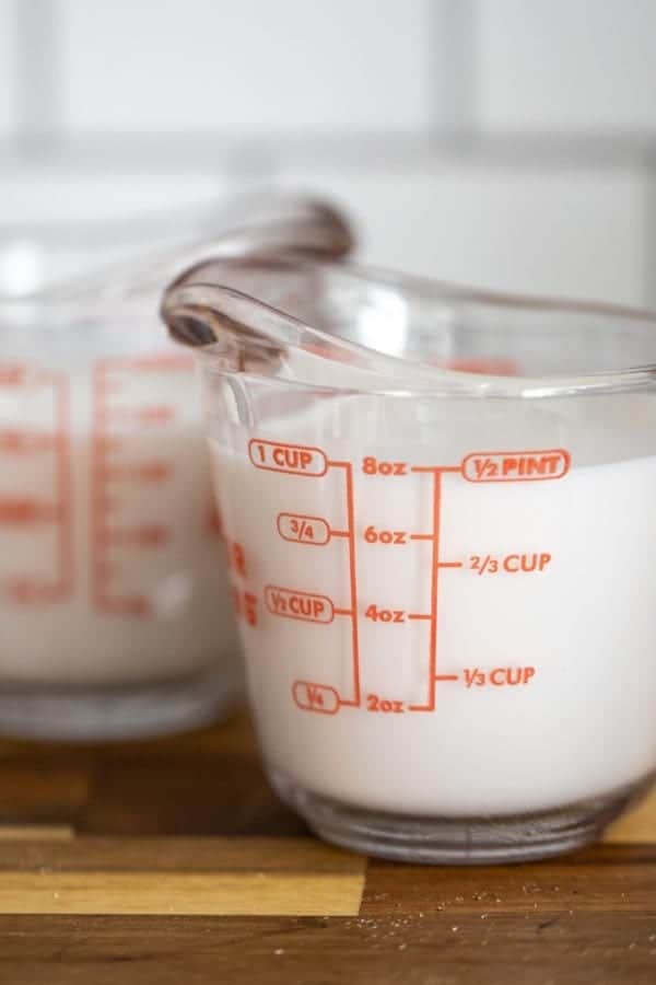 two liquid measuring cups full of coconut milk