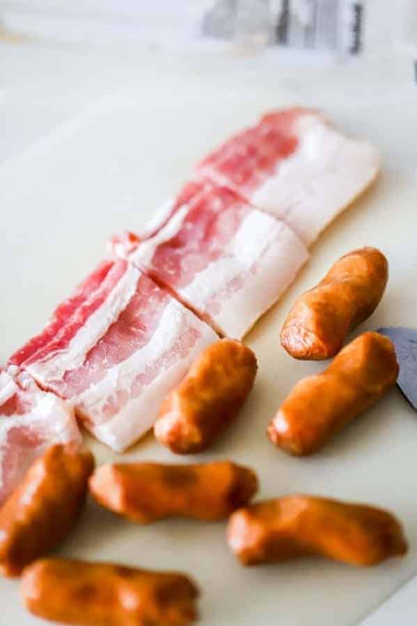 pieces of bacon next to unwrapped little smokies