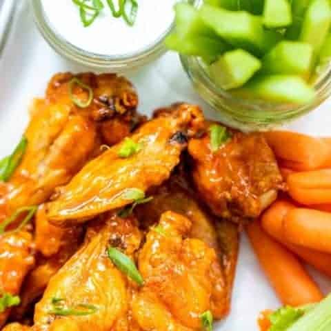 a plate of chicken wings with vegetables and ranch