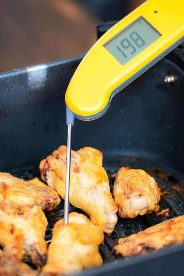 a thermoworks thermapen taking the temperature of a chicken wing cooked in the air fryer