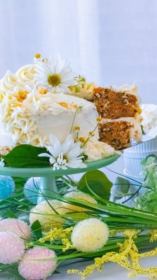 a slice of carrot cake being taken out of the larger cake