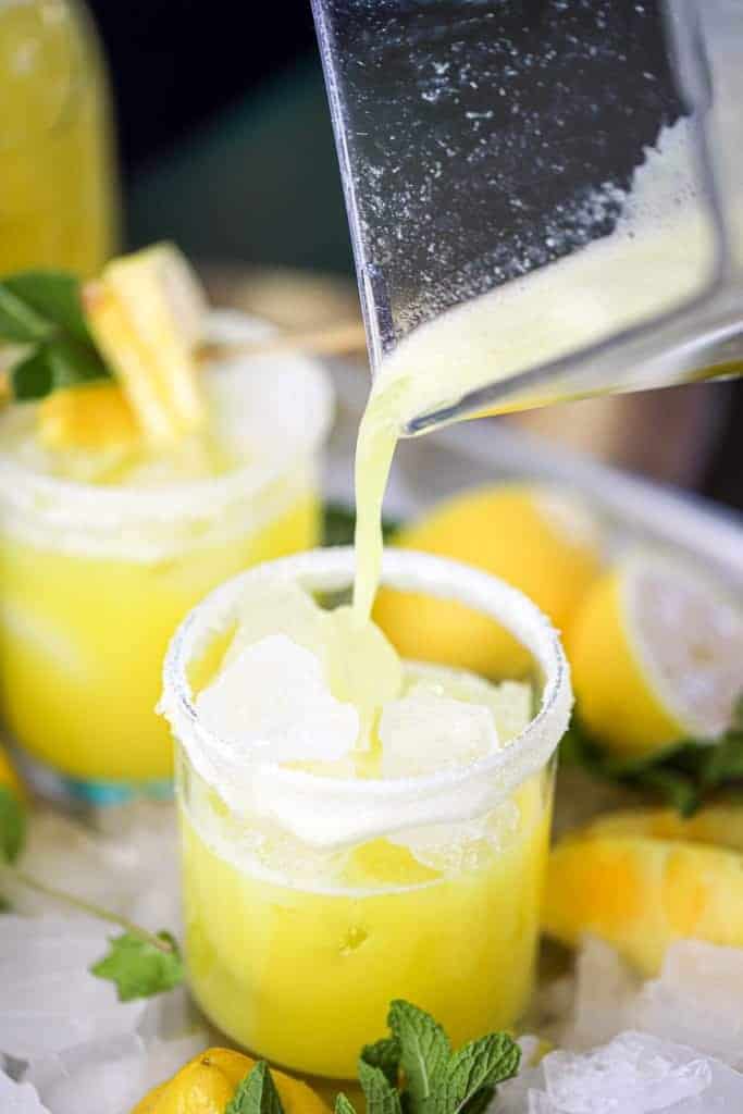 a pitcher pouring lemonade into a glass with ice