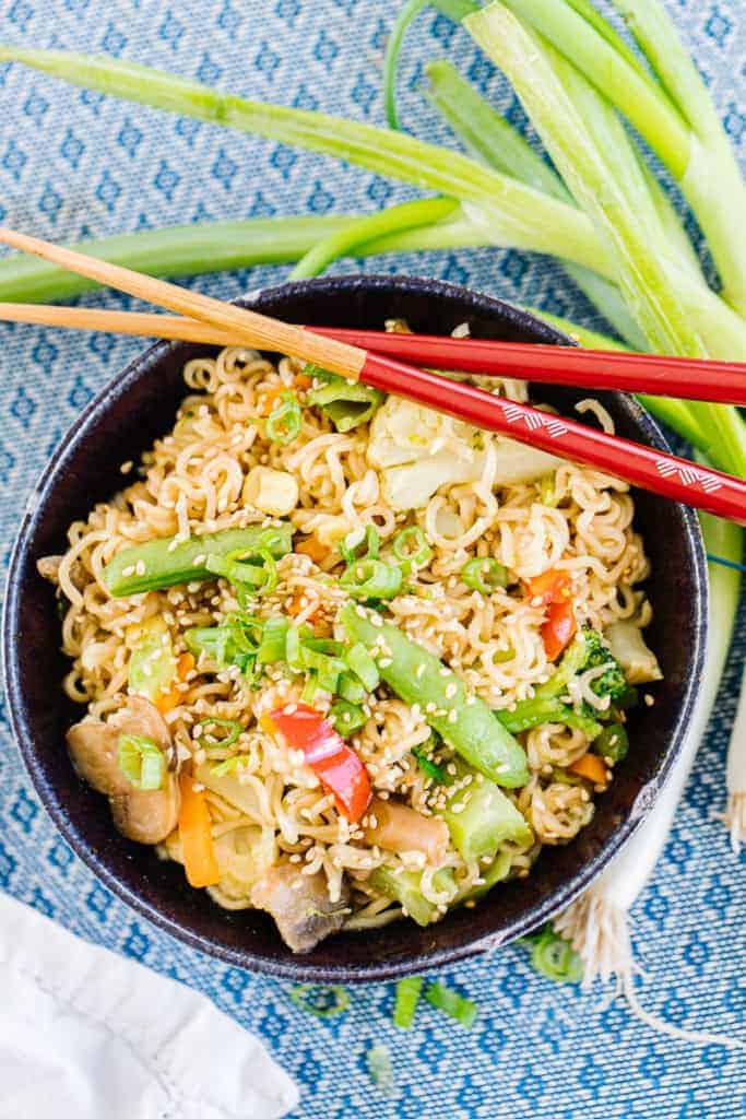 Top view of ramen stir fry with chopsticks surrounded by green onion