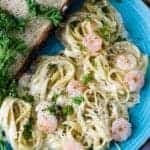 a plate of shrimp alfredo with bread on a blue plate