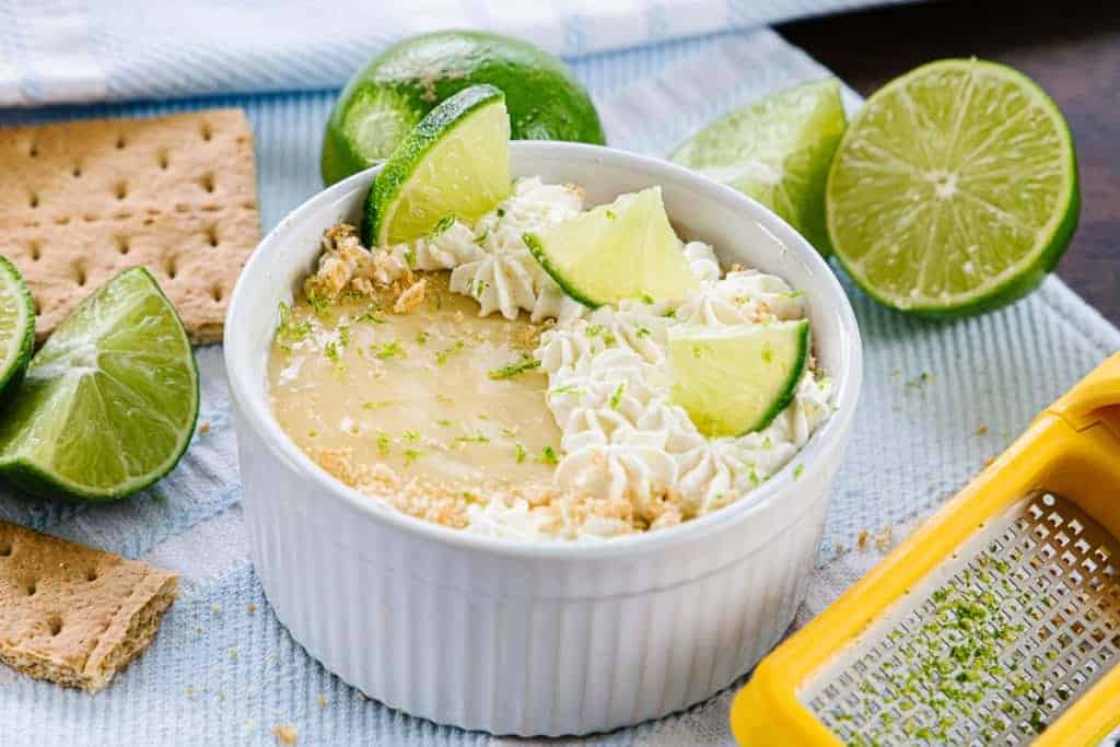 Key lime pie topped with cream, limes and surrounded by graham crackers, limes, and a lime zester