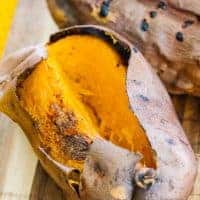 Two air fried sweet potatoes with one split open down the center