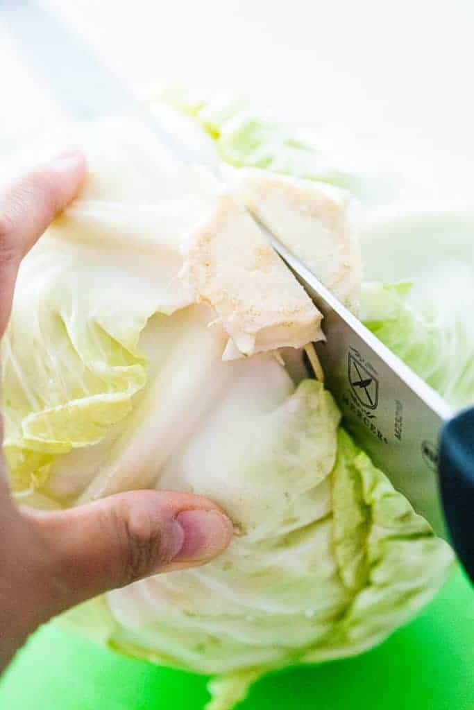 knife cutting cabbage in half from the bottom