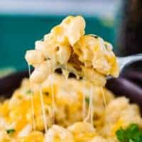 Fork lifting instant pot mac and cheese with cheesy strings coming from bowl of mac and cheese