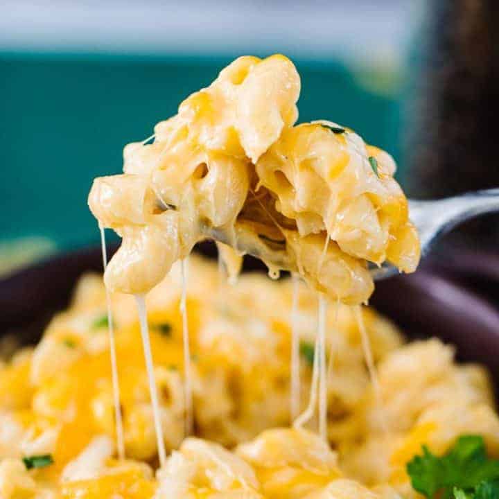 Fork lifting instant pot mac and cheese with cheesy strings coming from bowl of mac and cheese