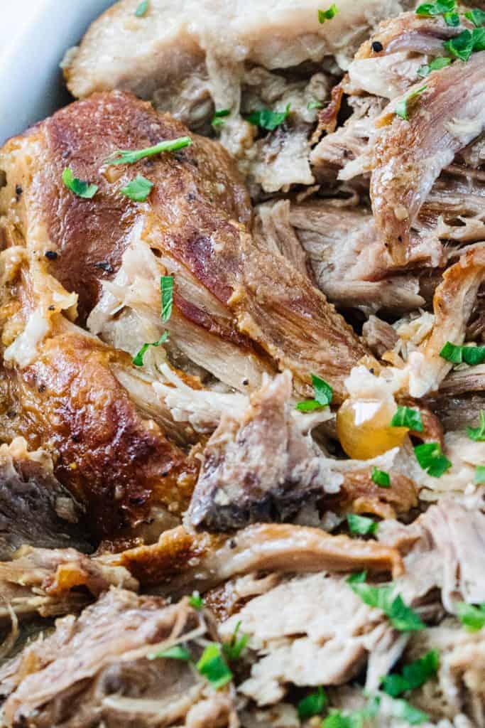Close up of shredded instant pot pork roast topped with green herbs