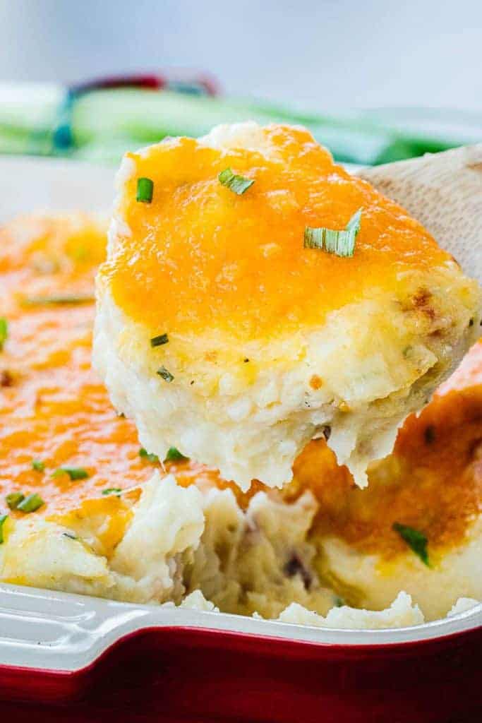 Close up of potato casserole scooped from pan topped with cheese and green onions