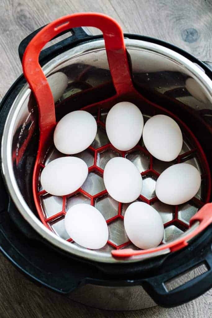 8 white eggs on red silicone trivet in instant pot