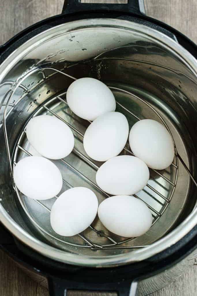eight eggs placed on lined metal trivet in instant pot