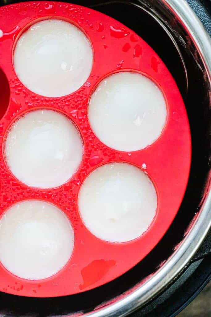 five cooked instant pot eggs in red silicone trivet in instant pot