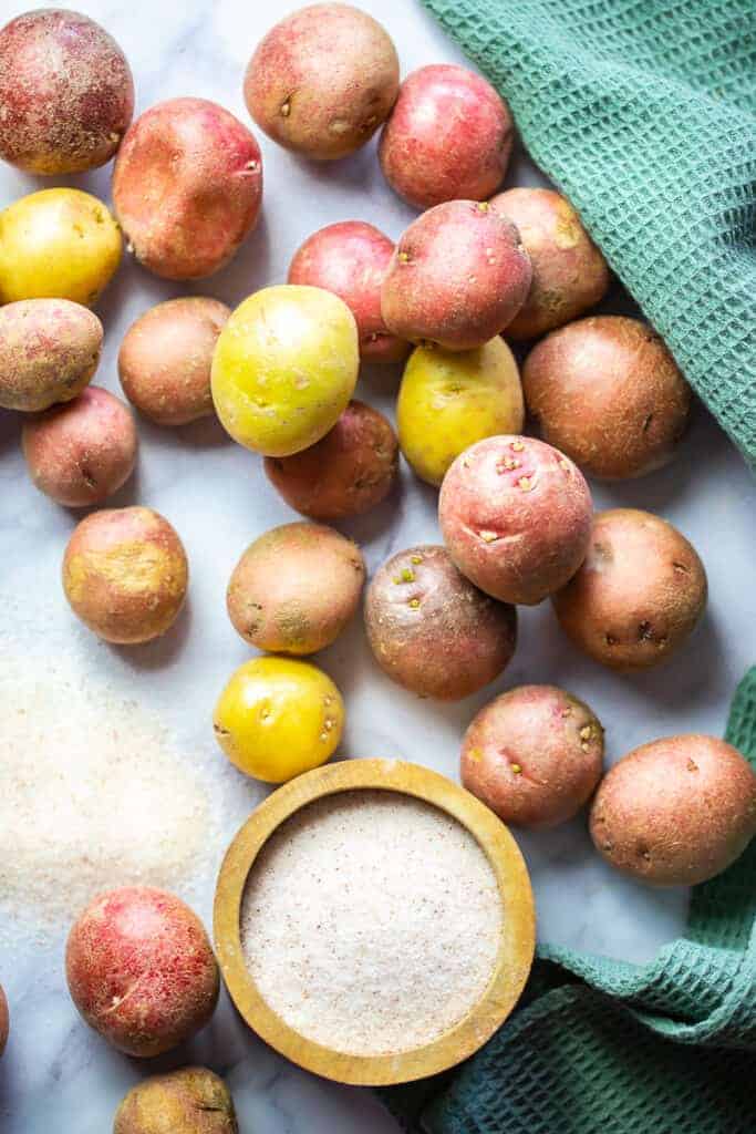 ingredients for salt potatoes- baby potatoes and a jar of salt with a green towel