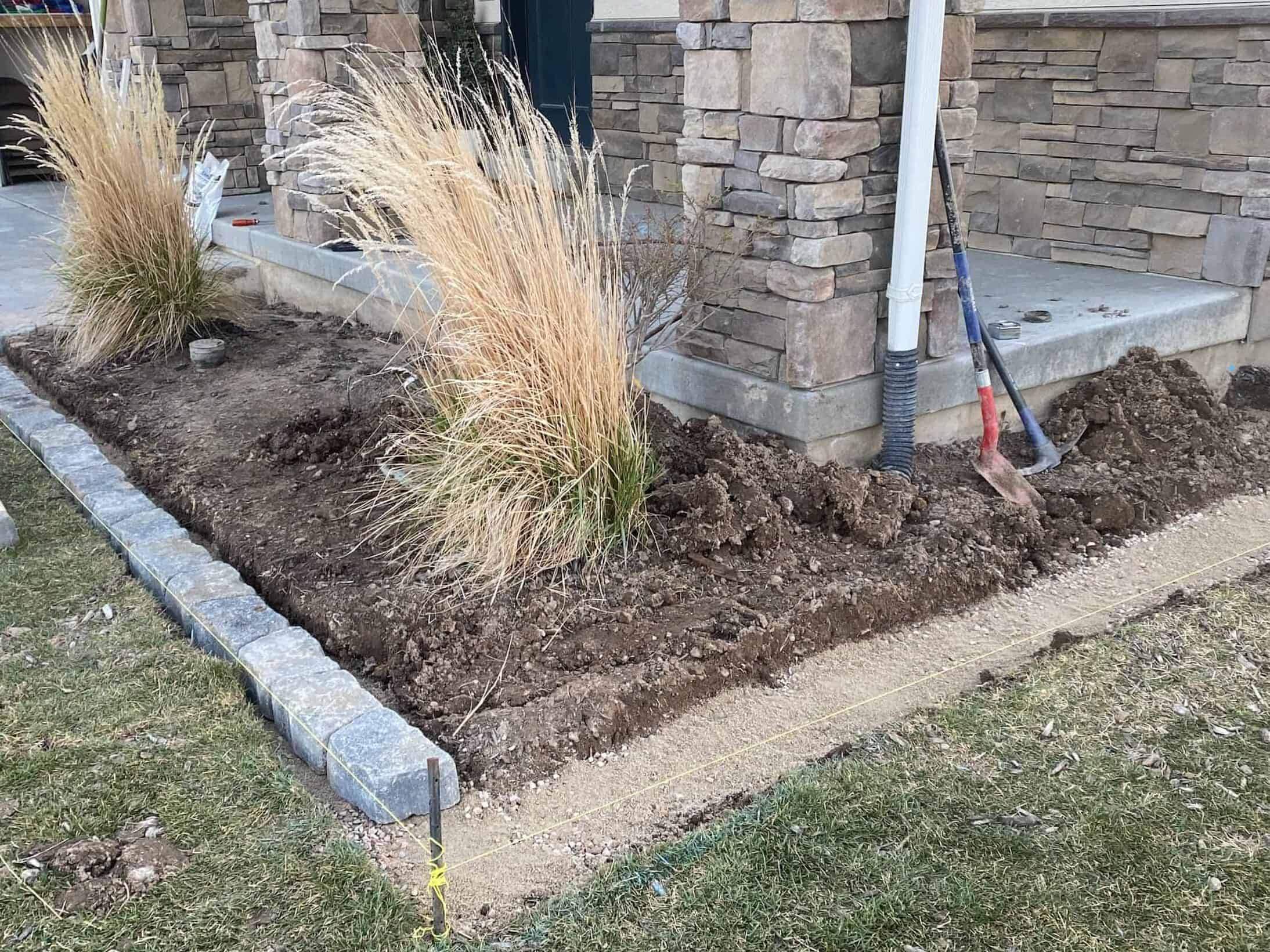 a flower bed being built in front of a front porch