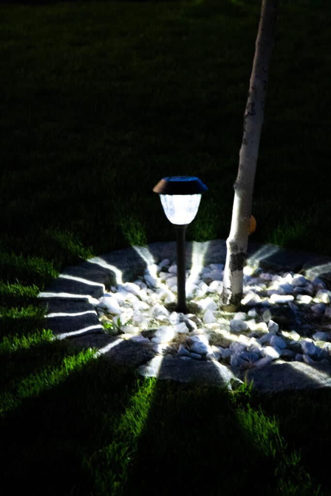 an led solar light shining brightly under a tree