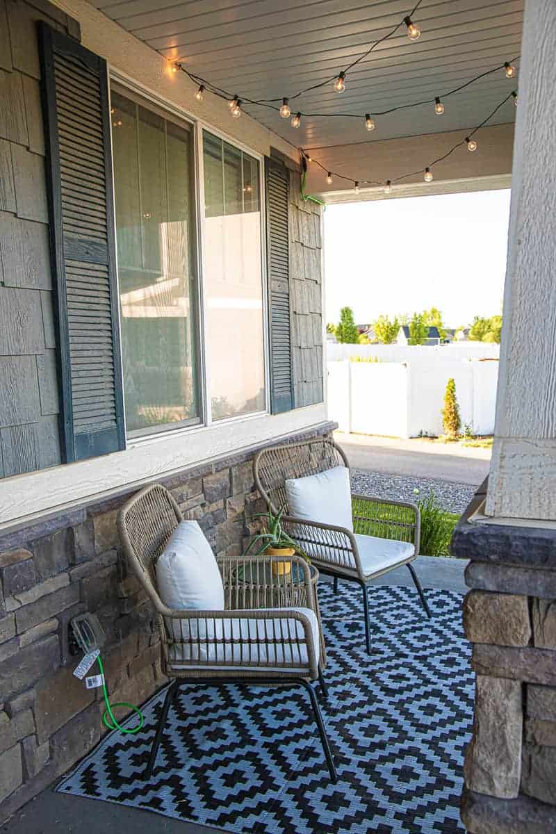 porch lights lit up in the daytime over two patio chairs