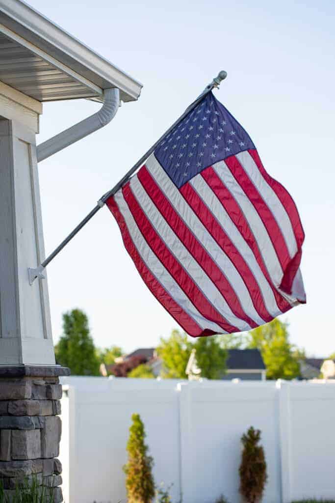 an american flag flying in front of a front porch