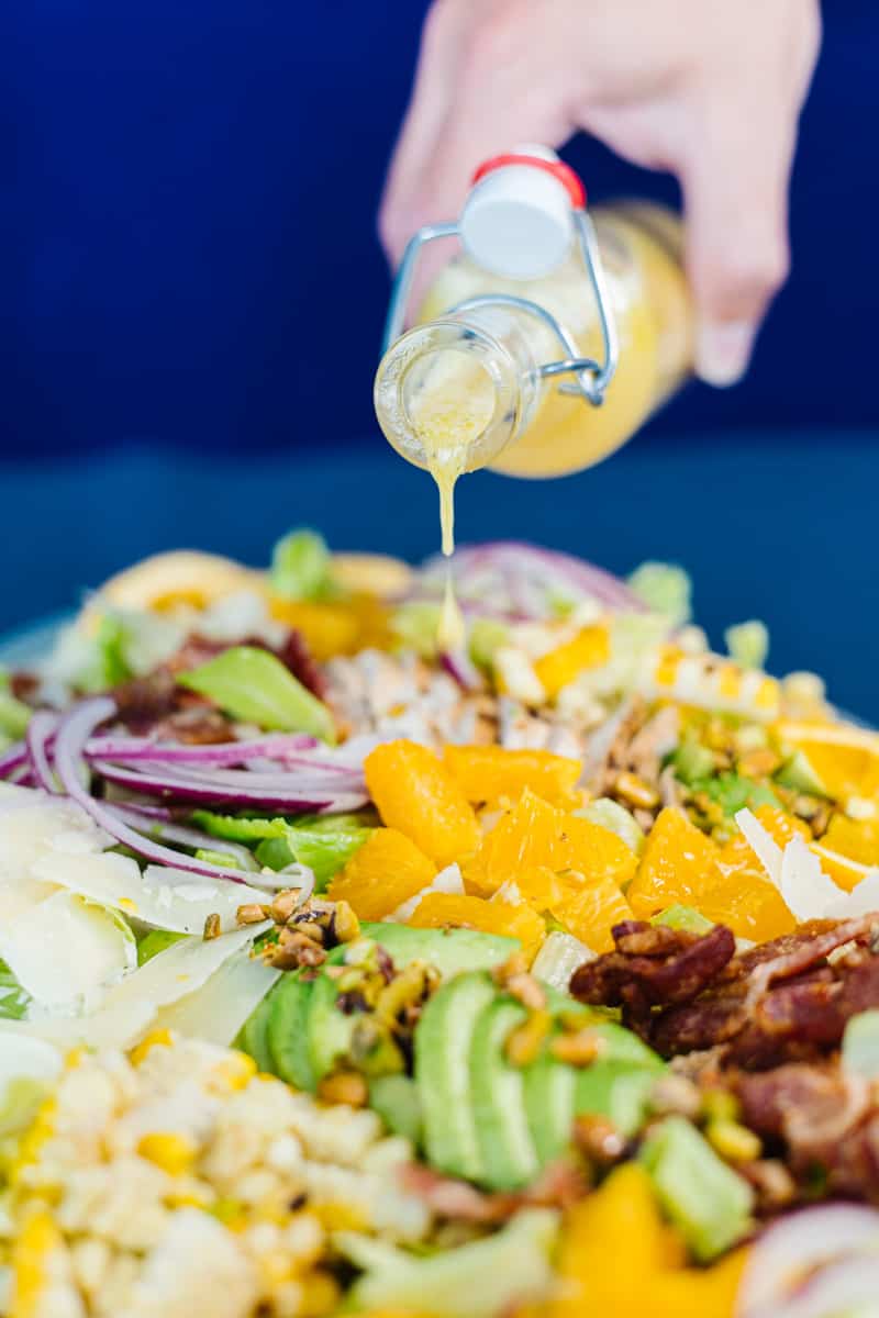 close up of vinaigrette being poured onto assembled catana salad