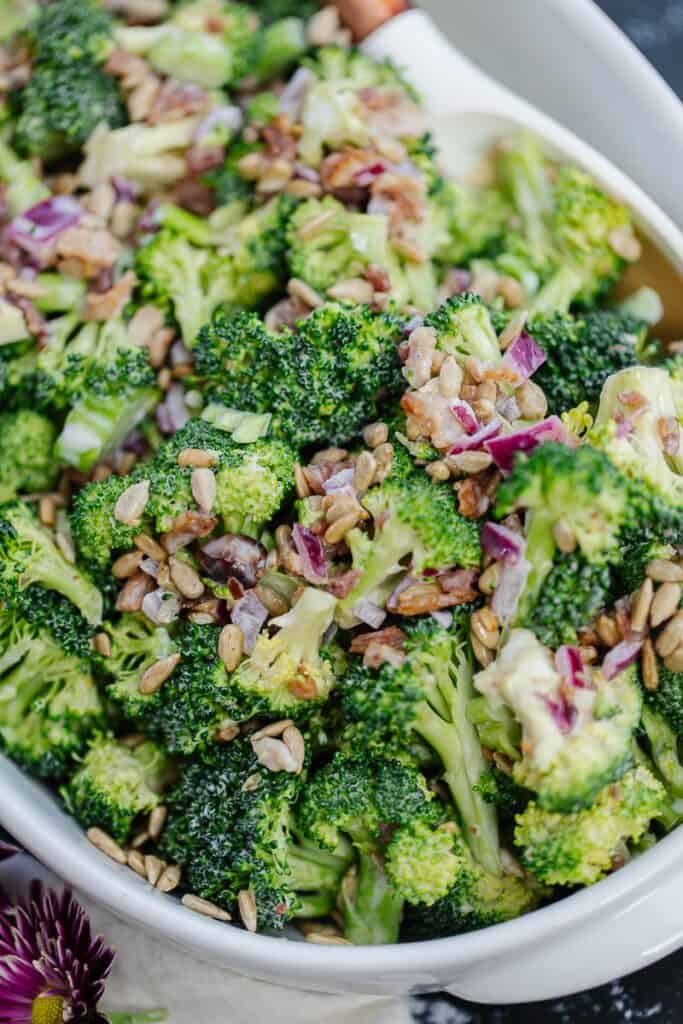 close up of broccoli salad in a large white serving bowl